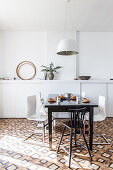 Dark dining table and designer chairs in front of white wall