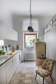 White kitchen counter, upholstered chair and fridge in kitchen with gallery