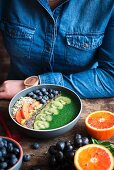 A smoothie bowl with kiwi, orange, blueberries, chia seeds and porridge oats