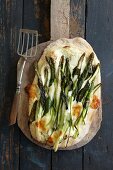 Wild garlic and asparagus pizza with parmesan on a pizza shovel (seen from above)