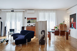 Designer sofa and dining area divided by screen made from cardboard tubes in open-plan interior