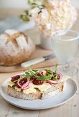 Belegtes Mehrkornbrot mit Käse, Marmelade, Zwiebeln und Rucola