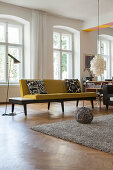 Yellow sofa and standard lamp in front of window in period apartment