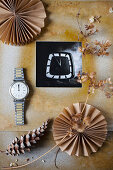 Schwarz-weißes Foto in DIY-Passepartout, Trockenblume, Armbanduhr, Zapfen und Papierrosetten
