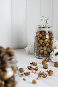Loose hazelnuts on a table and in a glass storage jar