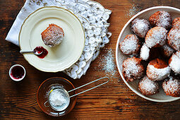 Doughnuts with icing sugar on an étagère and a plate with spoon of jam