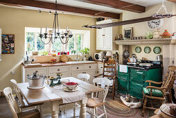 Dining table and green wood-fired stove in rustic kitchen