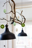 Hand-made felt flowers and Easter eggs hung from branch above pendant lamp
