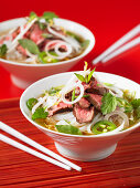 Two bowls of Pho Bo (Vietnamese noodle soup) with beef