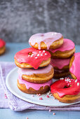 A stack of pink and red-glazed doughnuts