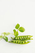 Two fresh pea pods against a white background