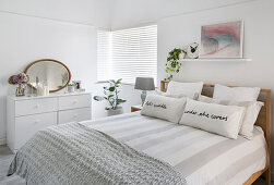 Double bed and chest of drawers in simple white bedroom