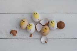 Painted Easter eggs and egg shells on white wooden surface