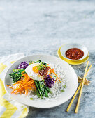 Rice with vegetables, fried egg and a spicy chilli sauce
