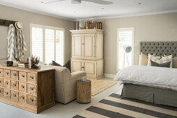 Double bed, wardrobe, sofa bed and antique apothecary's cabinet in sleeping area of open-plan interior