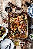 Whole butterflied roasted chicken with vegetables on wooden table