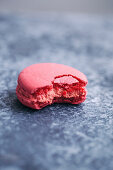 Half eaten pink macaron on grey background