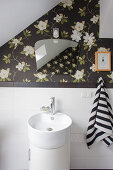 Vintage-style mirror on dark floral wallpaper above sink