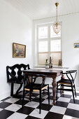 Designer chairs around old wooden table on chequered floor