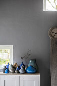 Collection of blue and grey vases against grey wall