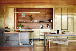 Kitchen and dining area in an open living room with patinated brass cladding