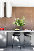 Barhocker an der Kochinsel in moderner Küche mit Holzfronten