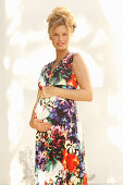 Schwangere Frau in ärmellosem Sommerkleid mit Blumenmuster