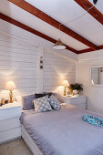 Schlafzimmer mit weiß gestrichener Holzverkleidung im Dachgeschoß