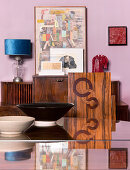 Bowls on dining table and chair with inlaid veneer backrest in front of sideboard