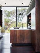Modern kitchen with dark wooden cupboards and glass wall