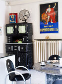 Black-painted kitchen dresser next to old advertising panel