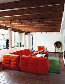 Orange designer sofa in living room with wooden ceiling beams