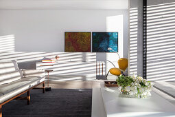Weisses Designer-Sofa vor Fensterfront mit Aluminium-Jalousie