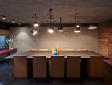 Designer lamp above long dining table in modern architect-designed house