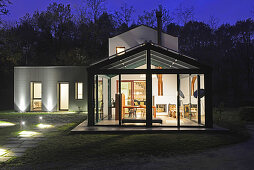 Illuminated house with glass façade at twilight