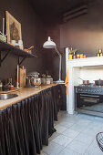 Kitchen counter with curtain front and cooker in kitchen with dark wall