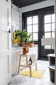 Houseplant on stepladder next to bathtub in renovated bathroom with balcony door