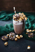A chocolate and oat drink, soy cream, chocolate sauce, donuts and caramel popcorn (vegan)