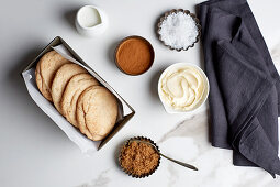 Snickerdoodle cookies with ingredients in vintage tins on a white marble table and black linen