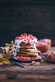 Stack of banana pancakes topped with soya yogurt and pomegranate seeds