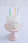 Kuchen mit bunten Zuckerperlen und Geburtstagskerzen
