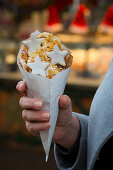 A hand holding a bubble waffle with cinnamon stars and almonds (Christmas)