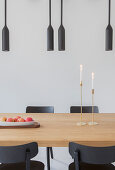 Black pendant lamps above dining table and black chairs