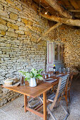 Set table in converted barn with stone wall