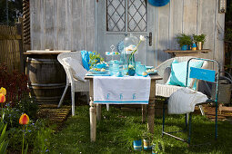 Table set in shades of blue with handmade decorations in spring garden