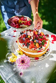 Strawberry sponge cake being decorated with flowers
