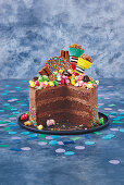 A chocolate buttercream cake with sprinkles, topped with popcorn and sweets