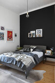 Grey double bed on animal-skin rug in bedroom with solid black and solid white walls
