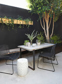 Table, chairs and bench against black wall of courtyard