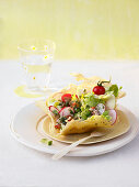 A Spring salad in a parmesan crisp with a herb vinaigrette